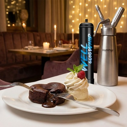 Decadent chocolate lava cake with molten center and whipped cream topped with a raspberry. Crisp table setup in a warmly lit, elegant restaurant setting.